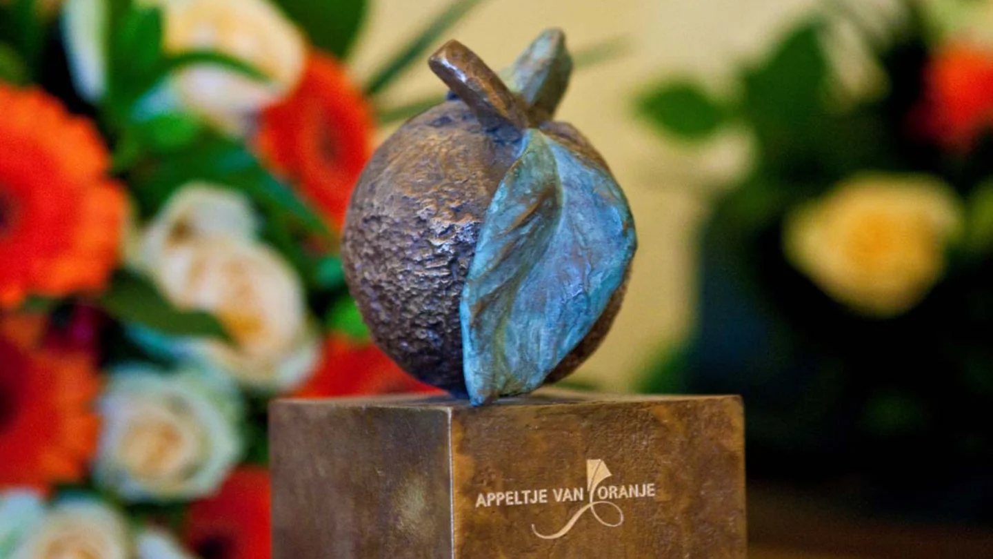 Het bronzen Appeltje van Oranje-beeldje tussen bloemen